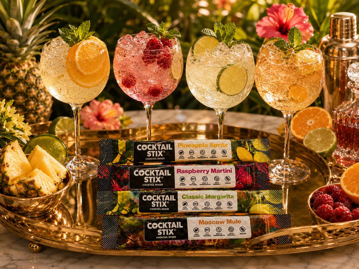 Cocktail Stix packets beside two polished drinks—one cocktail and one mocktail—on an upscale home bar or kitchen island.